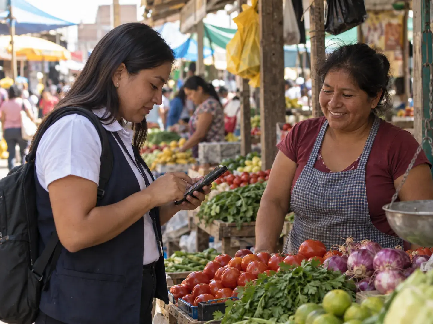 Asesora de crédito registrando el pago de una comerciante desde su celular en un mercado de Piura